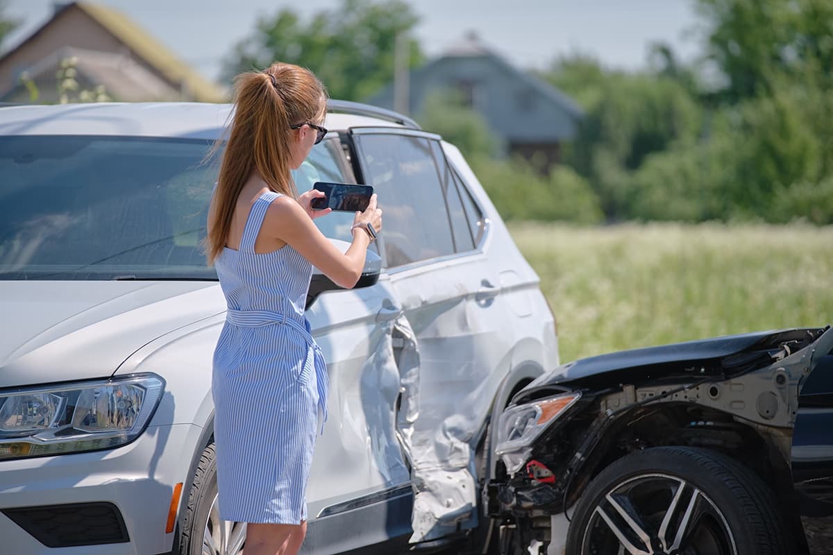 A woman photographing the damage to her car after a collision with another vehicle