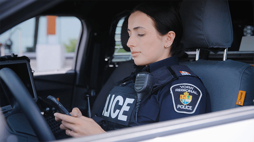A York Regional Police officer using a phone in the driver seat of a patrol vehicle