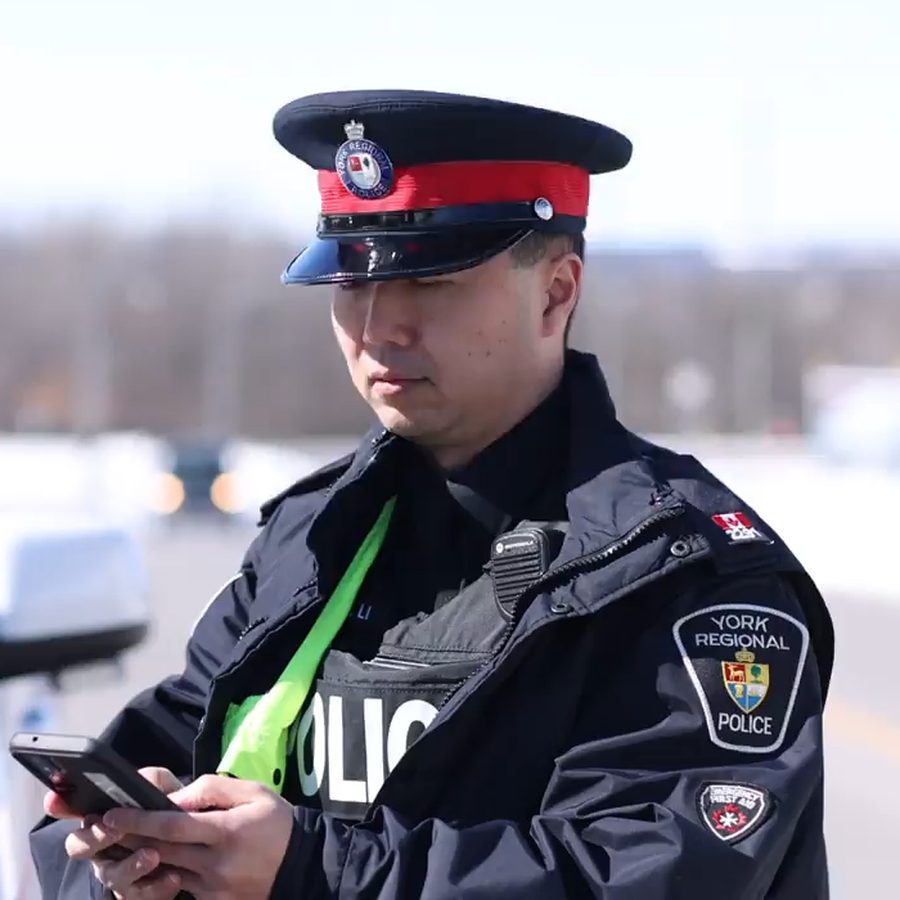 A York Regional Police officer taking notes on a handheld device while speaking with a driver at a roadside stop